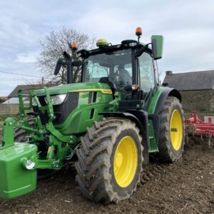 Un tracteur au travail avec une masse à l'avant et une charrue attelée