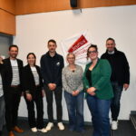 Des personnes dans une salle devant un drapeau jeunes agriculteurs