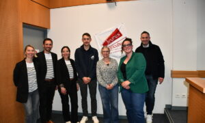 Des personnes dans une salle devant un drapeau jeunes agriculteurs