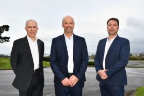 Des personnes en costume posent en extérieur