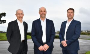 Des personnes en costume posent en extérieur