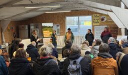Une assemblée de personnes assises de dos face à cinq interlocuteurs debout
