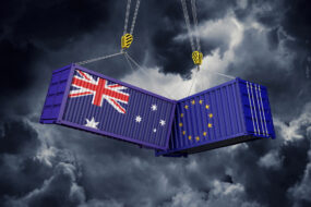 Infographie de 2 containers, un avec le drapeau australien et l'autre avec le drapeau européen. Ils sont suspendus et se cognent dans un ciel d'orage
