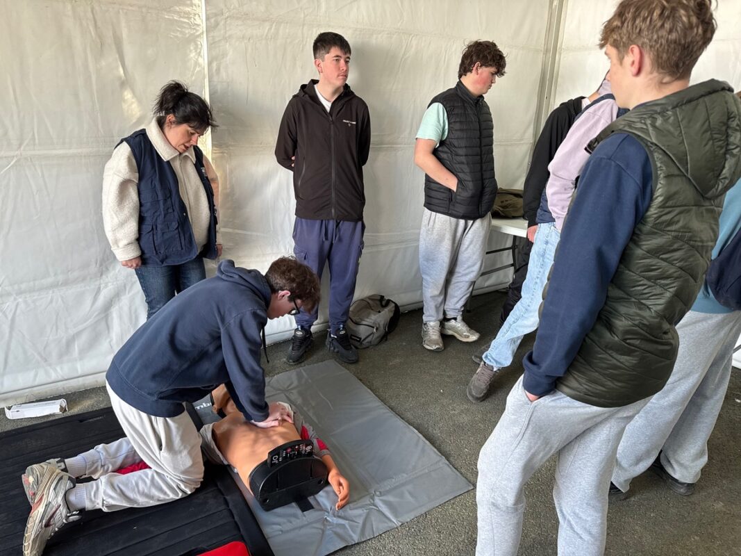 Au milieu de ses camarades, un élève pratique un massage cardiaque sur un mannequin