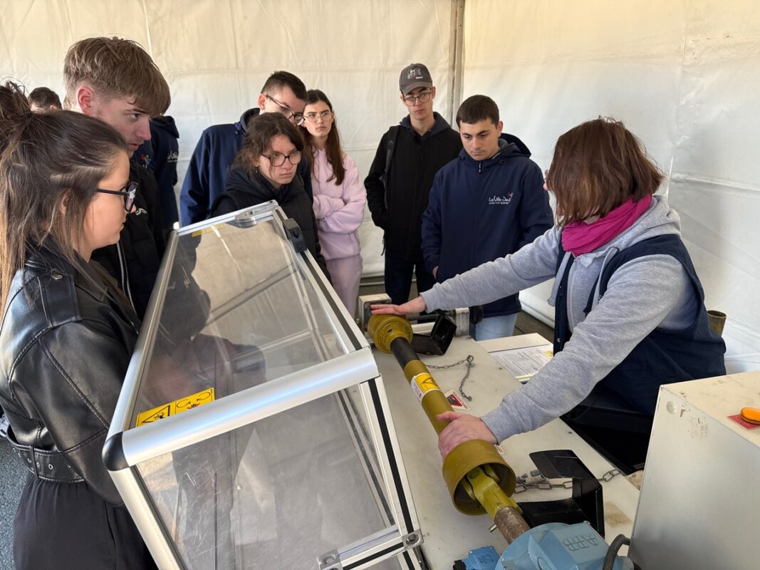 Une femme manipule un cardan de tracteur devant des élèves