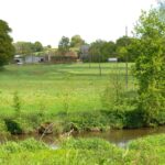 Un paysage de campagne verdoyant traversé au premier plan par une rivière