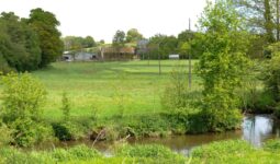 Un paysage de campagne verdoyant traversé au premier plan par une rivière