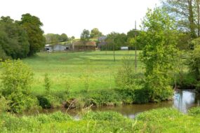 Un paysage de campagne verdoyant traversé au premier plan par une rivière