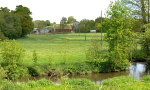 Un paysage de campagne verdoyant traversé au premier plan par une rivière