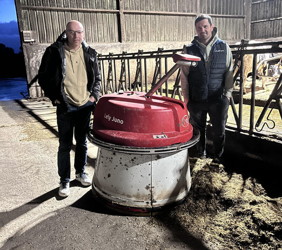 Deux hommes autour d'un robot repousse fourrage dans une stabulation bovine - Illustration Modernisation et autonomie au Gaec Ar Maneriou