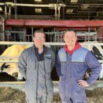 deux éleveurs devant une table d'alimentation dans une stabulation