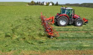 Un tracteur avec une faneuse attelée au champ