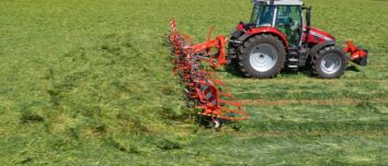 Un tracteur avec une faneuse attelée au champ