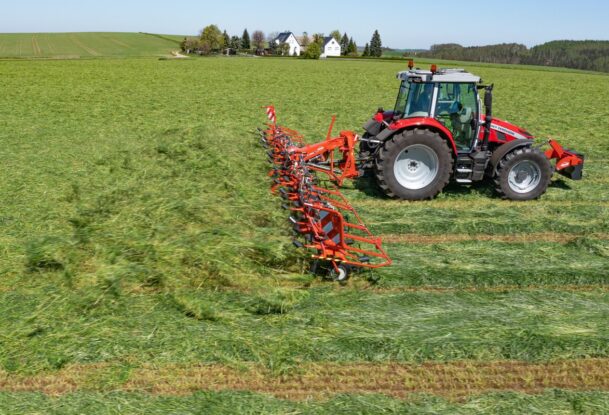 Un tracteur avec une faneuse attelée au champ