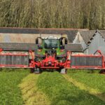 Un tracteur équipé d'un groupe de fauche coupe de l'herbe dans une prairie