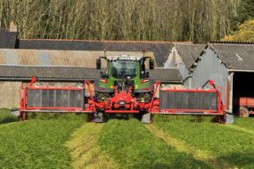 Un tracteur équipé d'un groupe de fauche coupe de l'herbe dans une prairie