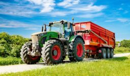 Un tracteur avec une remoque sur une petite route