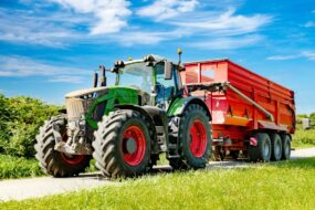Un tracteur avec une remoque sur une petite route