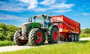 Un tracteur avec une remoque sur une petite route