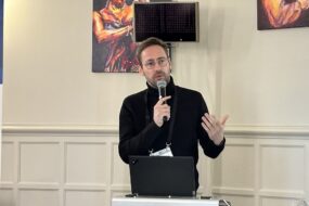 Un homme dans une salle en train de parler avec un micro à la main