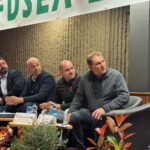 Quatre homme assis autour d'une table regardent sur leur gauche