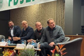 Quatre homme assis autour d'une table regardent sur leur gauche