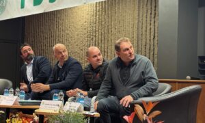 Quatre homme assis autour d'une table regardent sur leur gauche