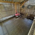 Un automate aspirateur de lisier dans une enceinte bardée de claire-voie dans un bâtiment d'élevage pour bovins