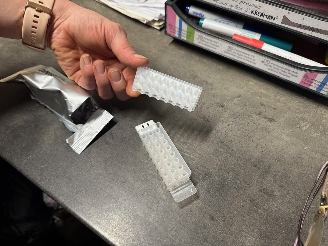 Une main présente une cassette d'analyse de lait