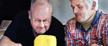 Deux hommes observent et sentent une motte de beurre artisanale posée sur une planche