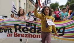 Une fillette devant une banderolle lors du départ d'une course de relais à pieds avec le bâton témoin à la main