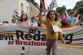 Une fillette devant une banderolle lors du départ d'une course de relais à pieds avec le bâton témoin à la main