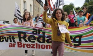 Une fillette devant une banderolle lors du départ d'une course de relais à pieds avec le bâton témoin à la main