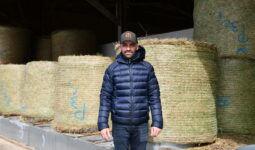 un éleveur devant des bottes de foin en round
