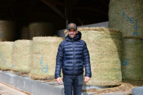 un éleveur devant des bottes de foin en round
