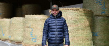 un éleveur devant des bottes de foin en round