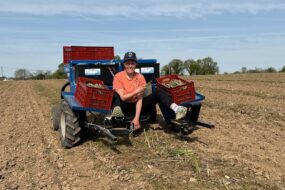 Une femme assise sur une machine en train de récolter des asperges vertes dans un champ