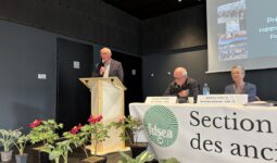 Une personne parle dans un micro derrière un pupitre lors d'une assemblée