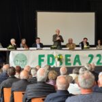 Huit personnes à la tribune d'une assemblée générale devant un public de séniors