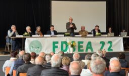 Huit personnes à la tribune d'une assemblée générale devant un public de séniors