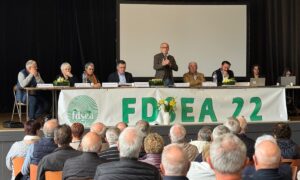 Huit personnes à la tribune d'une assemblée générale devant un public de séniors