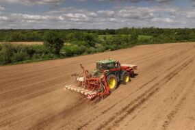 Vue aérienne d'un tracteur en train de semer du maïs dans un champ