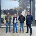 Trois hommes et une femme devant un poster de vaches laitières