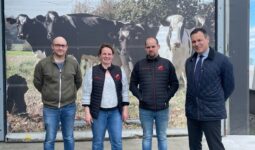Trois hommes et une femme devant un poster de vaches laitières