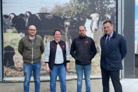 Trois hommes et une femme devant un poster de vaches laitières