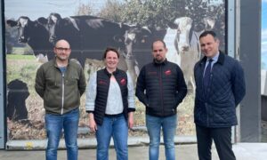 Trois hommes et une femme devant un poster de vaches laitières