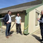 Des personnes devant un bâtiment d'élevage de volailles