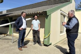 Des personnes devant un bâtiment d'élevage de volailles