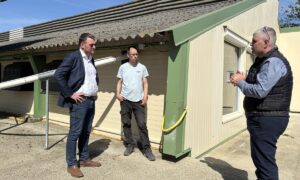 Des personnes devant un bâtiment d'élevage de volailles