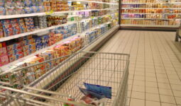 Un caddie dans une allée de supermarché au rayon yaourt